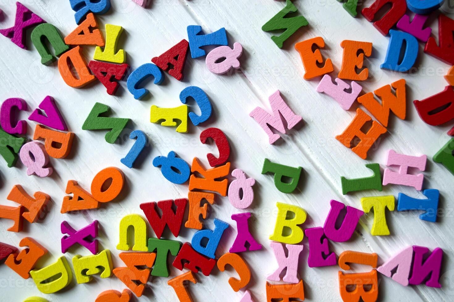Multicolor letters on a white wooden background. Colorful wooden alphabet on a table. photo