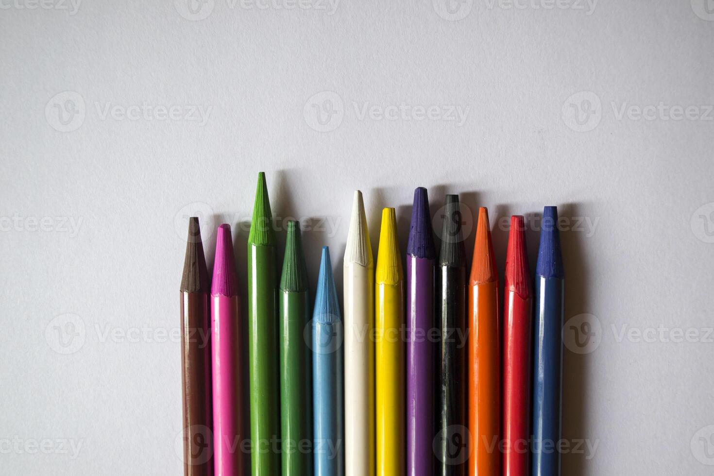 Multicolored pencils on white background. A palette of pencils on a table, close up. photo