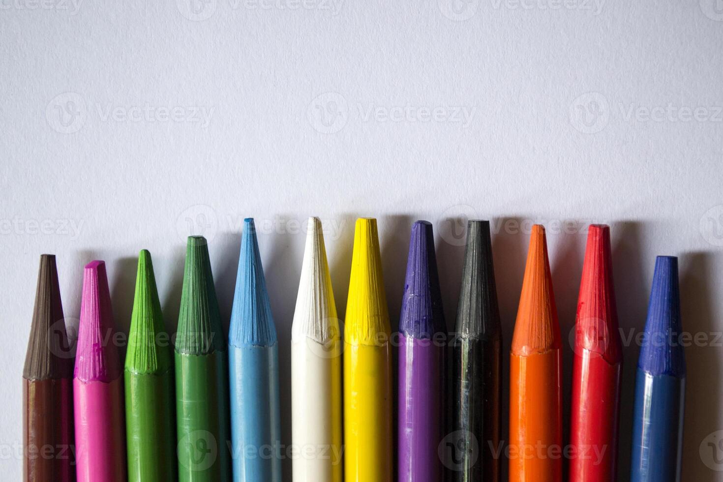 Multicolored pencils on white background. A palette of pencils on a table, close up. photo