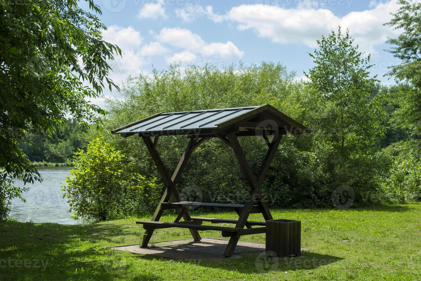 Summer arbor on the green meadow near lake. photo