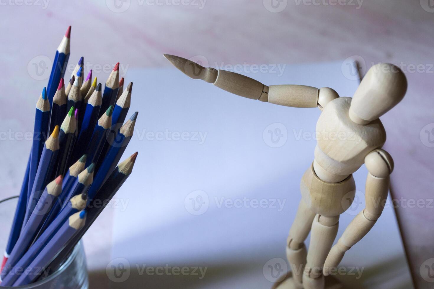 Colored pencils, empty paper and dummy for drawing on the table. photo