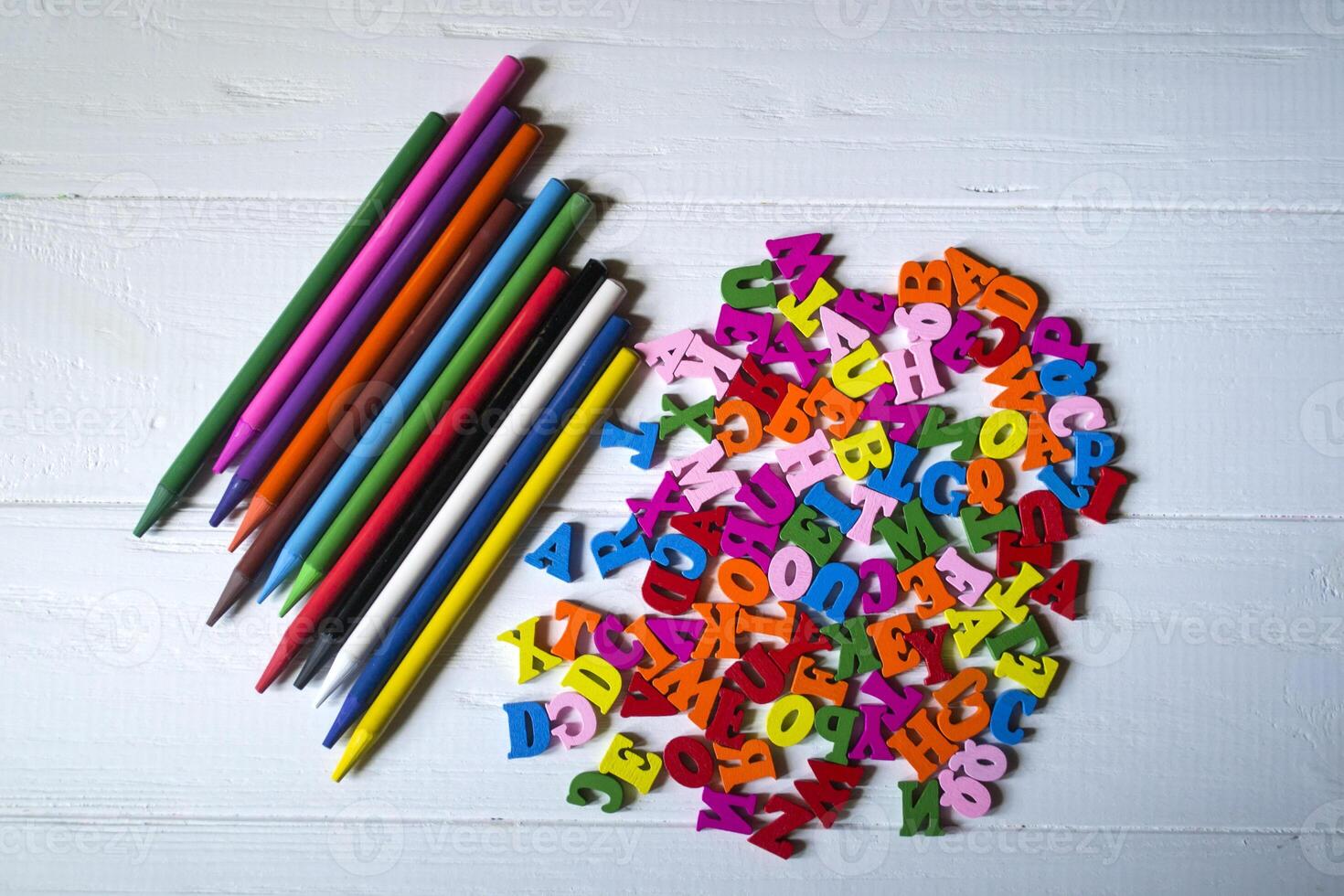 Multicolor letters and set of pencils on the table. Colorful wooden alphabet and pencils on a table. photo