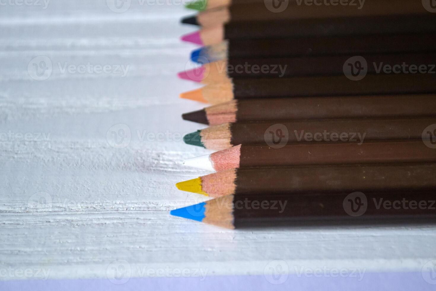 Multicolored pencils on white background. A palette of pencils on a table, close up. photo