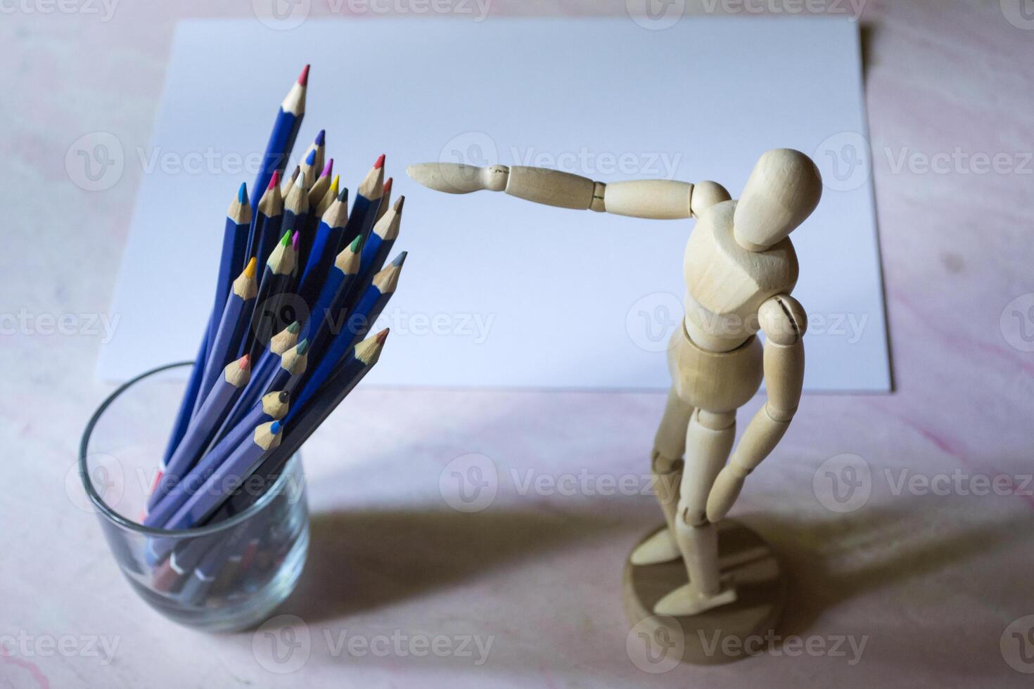 Colored pencils, empty paper and dummy for drawing on the table. photo