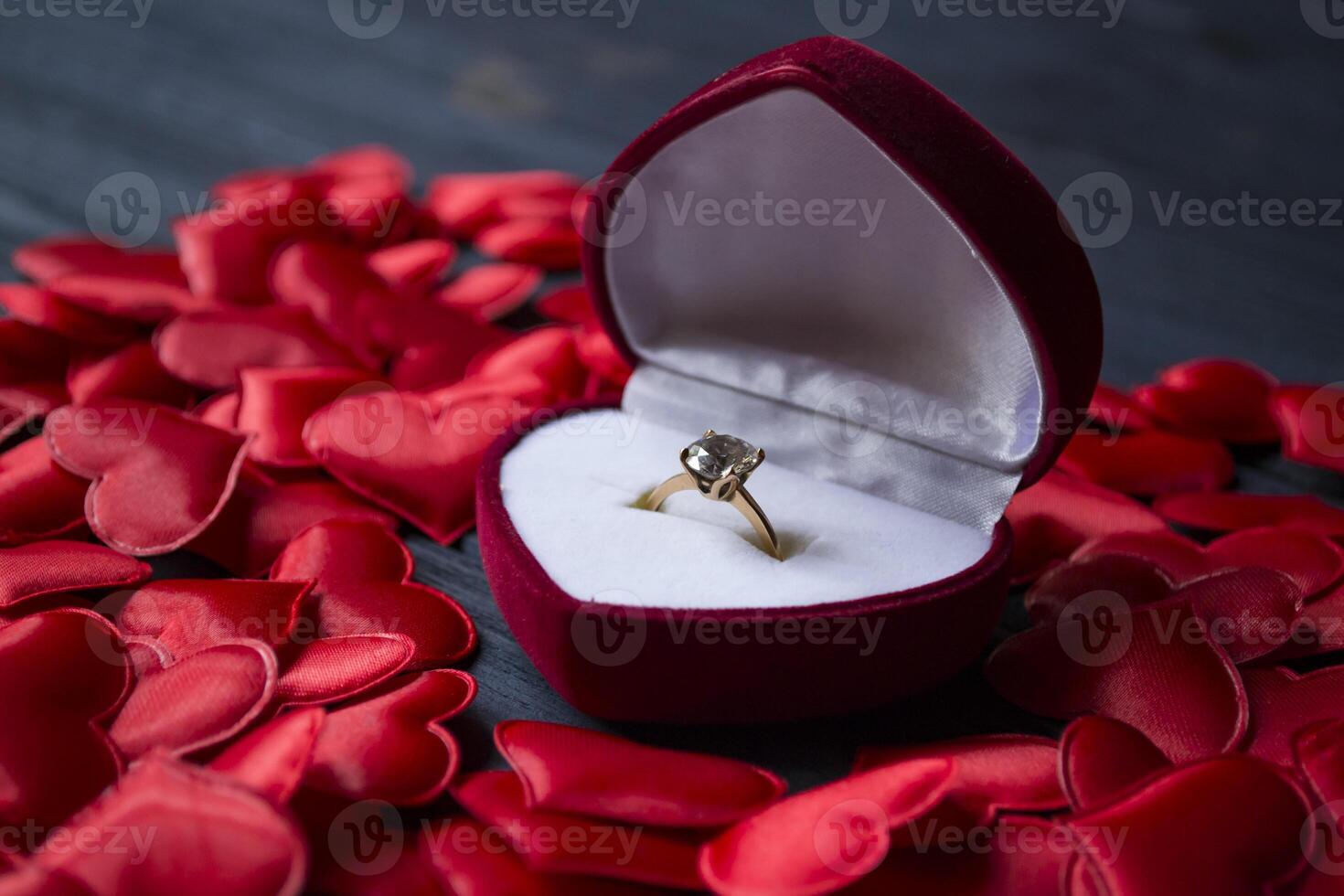 Engagement ring in a red box on a love hearts background. photo