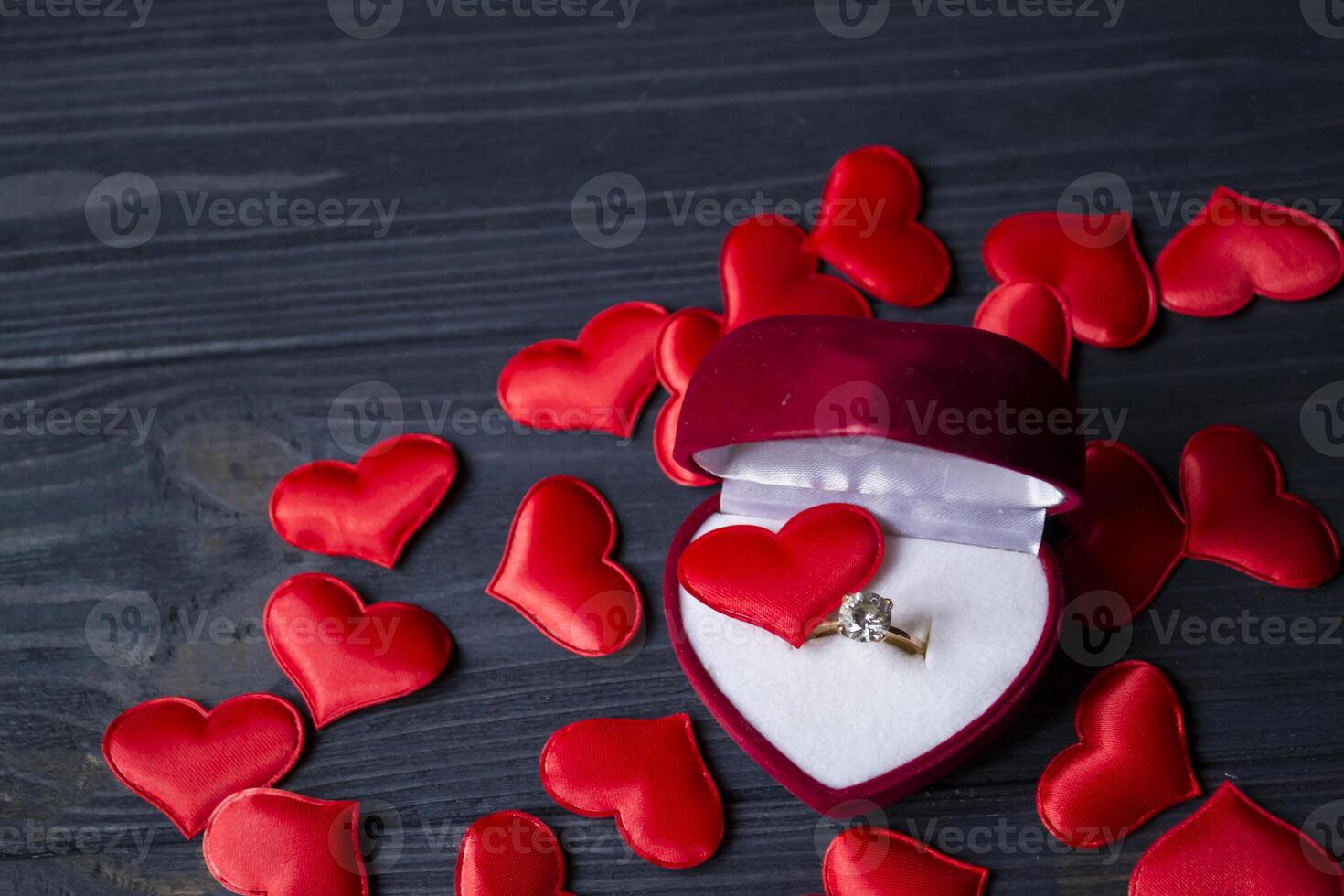 Engagement ring in a red box on a love hearts background. photo