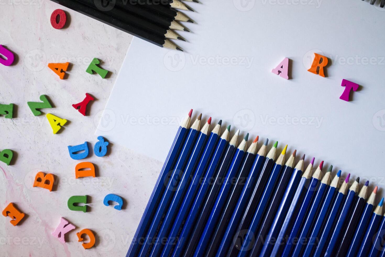 Multicolor letters and set of pencils on the table. Colorful wooden alphabet and pencils on a table. photo