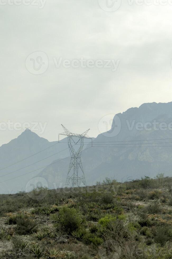 Power lines in a field with mountains photo