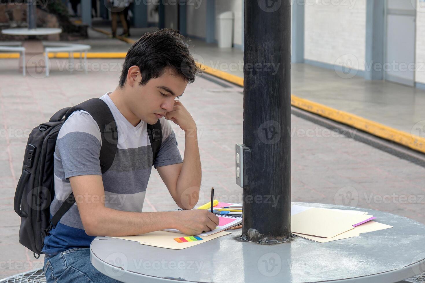 un estudiante sentado a un colegio mesa escritura en un pedazo de papel foto