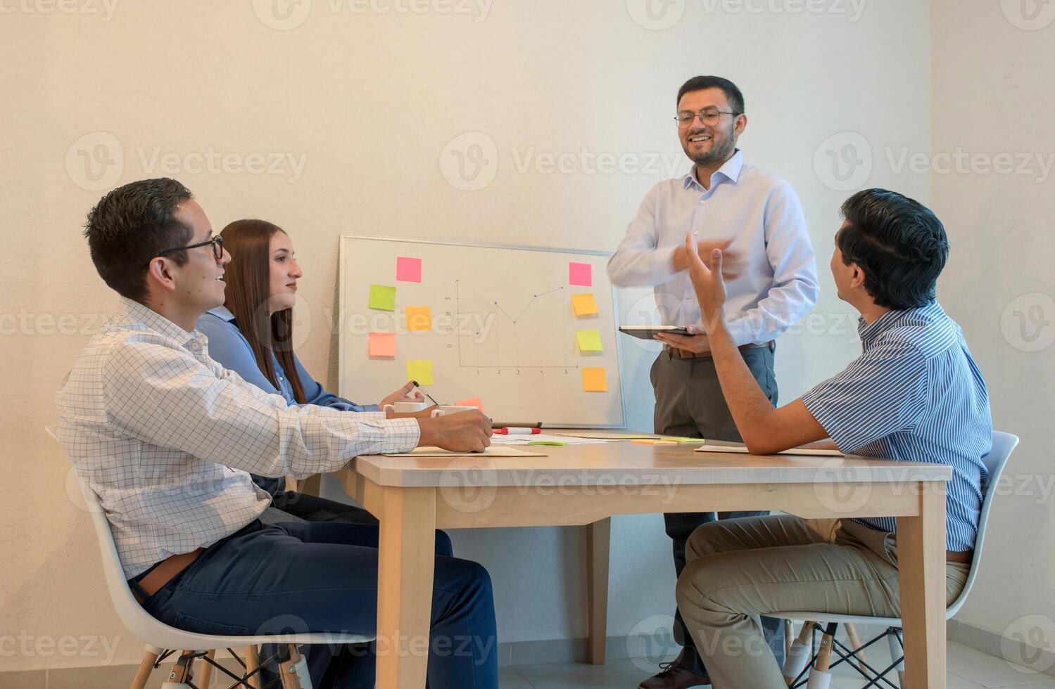 A man standing in front of a group of people sitting around a table photo