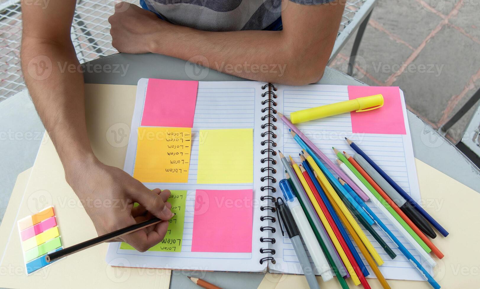 A student writing in a notebook and making notes on post its photo