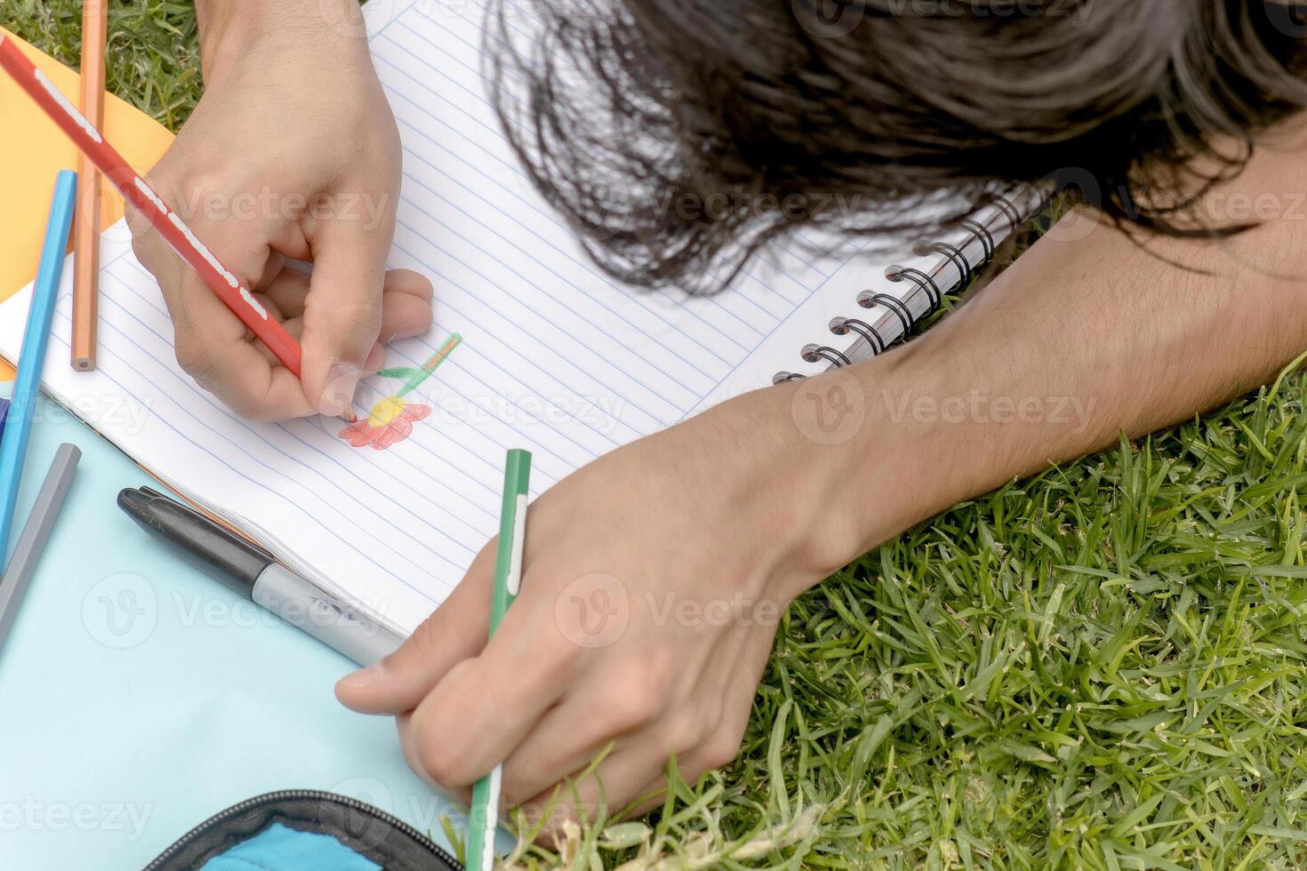 A person drawing a flower in a notebook photo