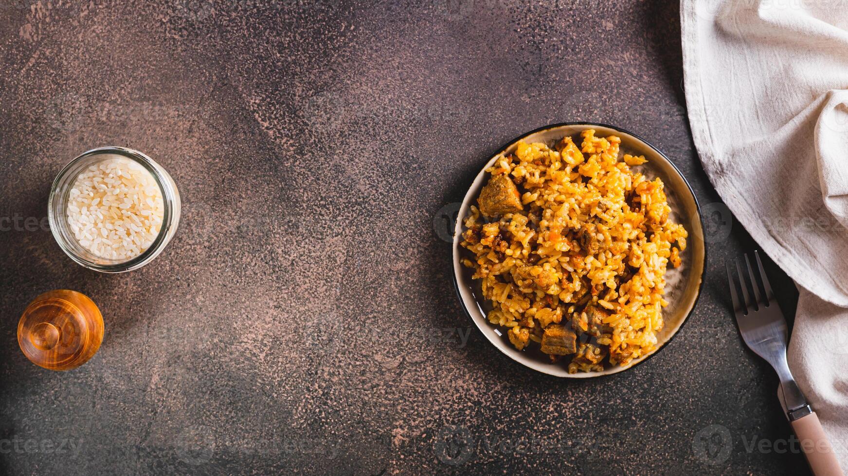 Traditional spicy pilaf with rice and meat on a plate on the table top view web banner photo