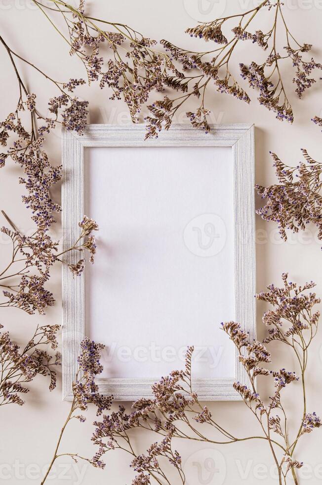 vacío foto marco rodeado por seco flores en un ligero antecedentes parte superior y vertical ver