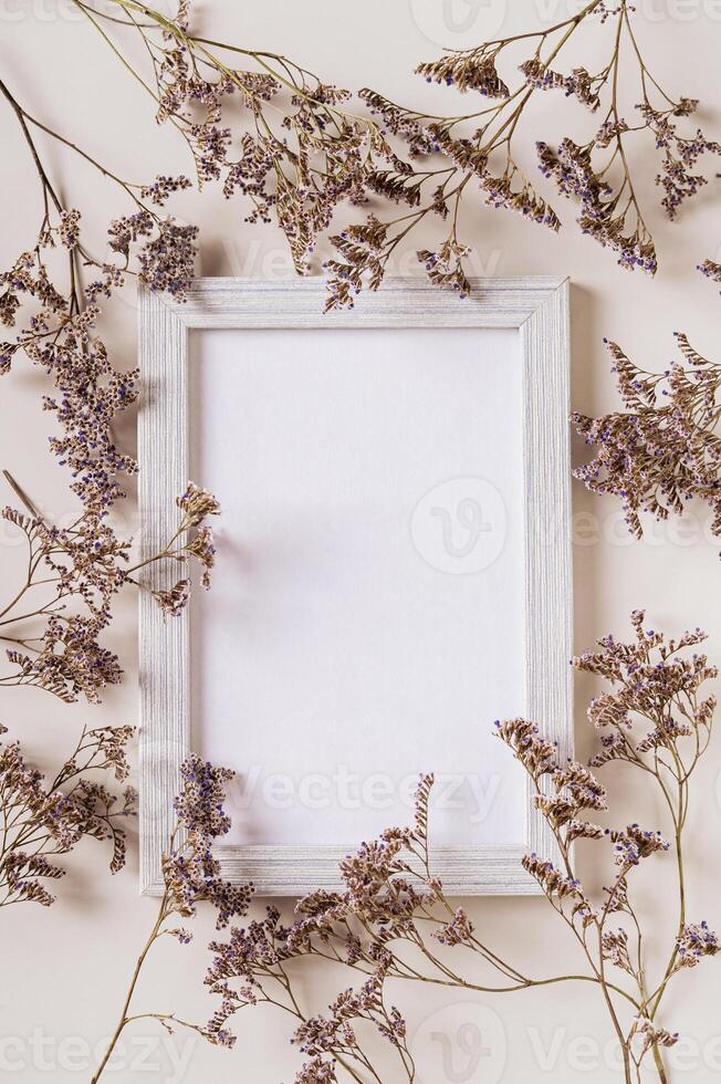 Empty photo frame surrounded by dried flowers on a light background top and vertical view