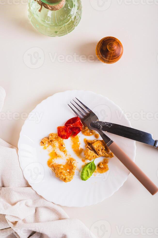 Food waste and cutlery on a dirty plate on the table top and vertical view photo