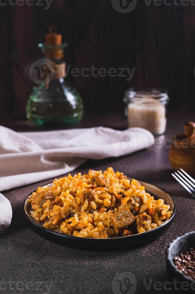 Delicious Asian pilaf with meat on a plate on the table vertical view photo