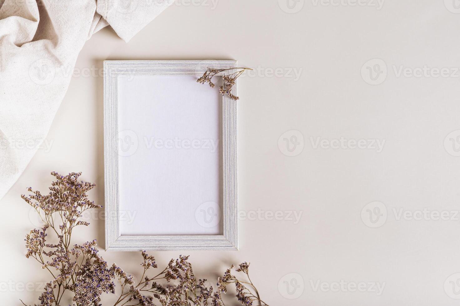 Empty photo frame, dried flowers and fabric on a light background top view