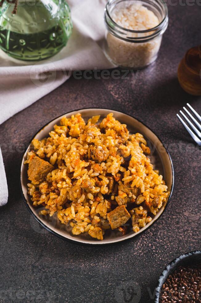 Traditional spicy pilaf with rice and meat on a plate on the table vertical view photo