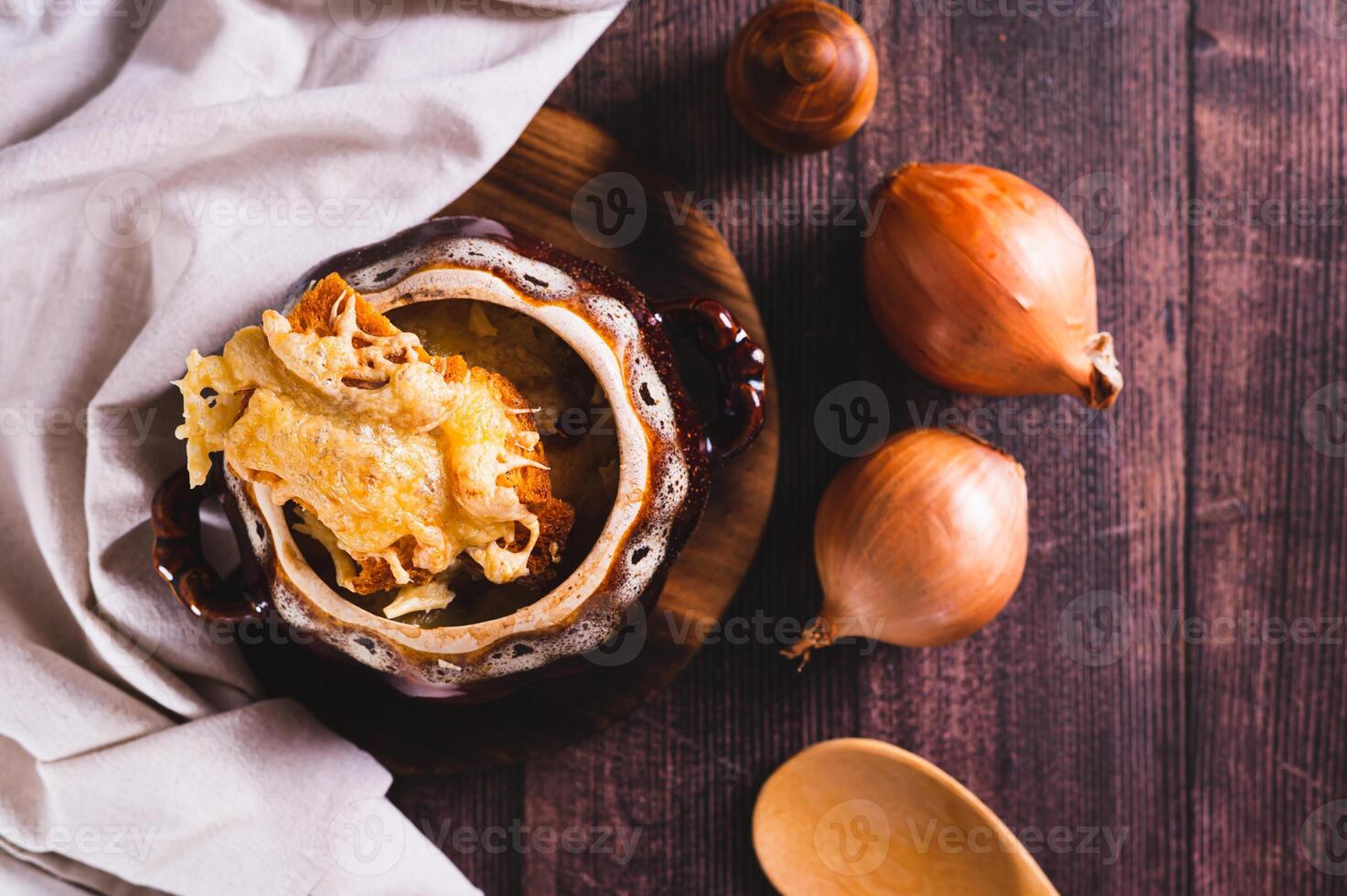 French onion soup with melted cheese and croutons in a pot on the table top view photo