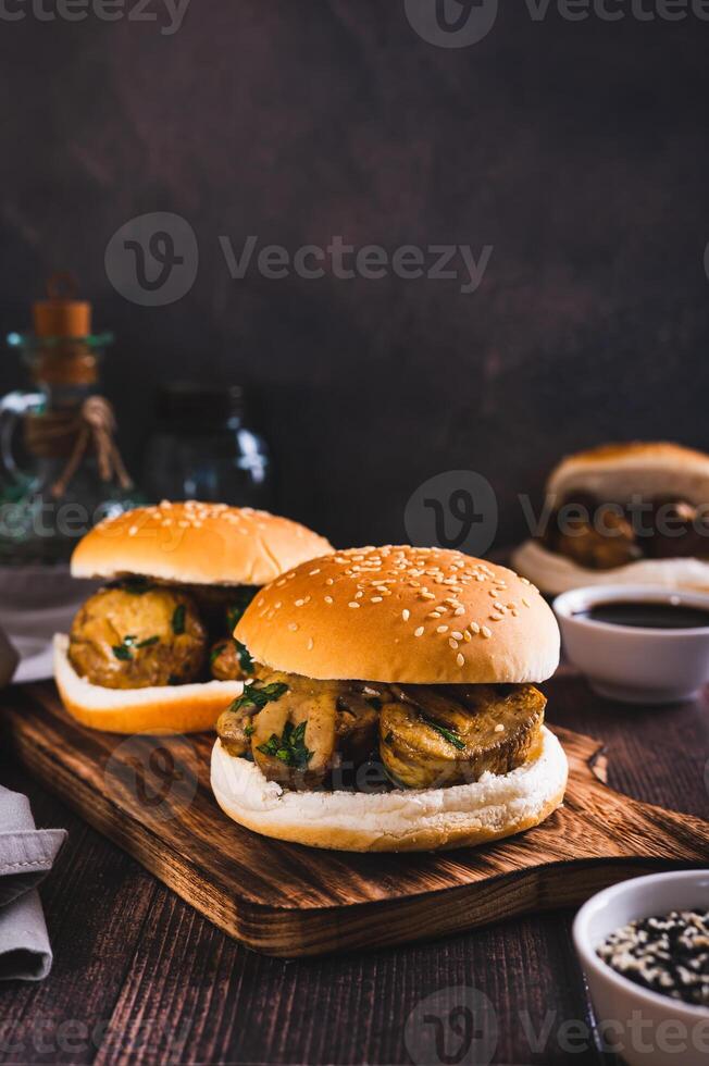 Appetizing burgers with grilled mushrooms and herbs on a wooden board vertical view photo