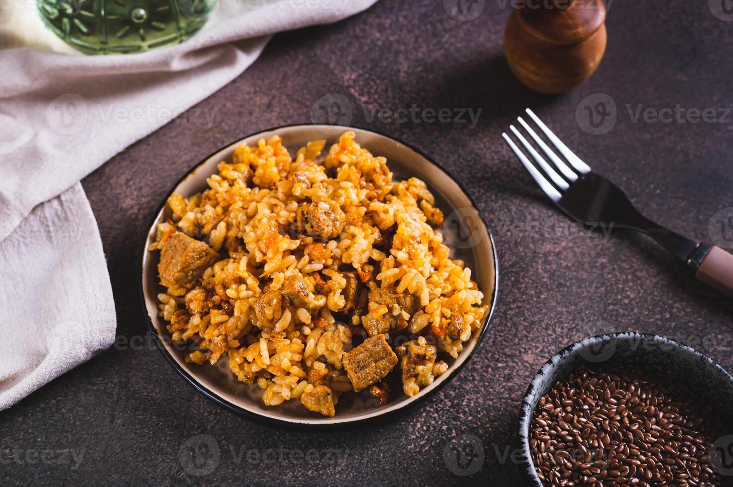 Traditional spicy pilaf with rice and meat on a plate on the table photo