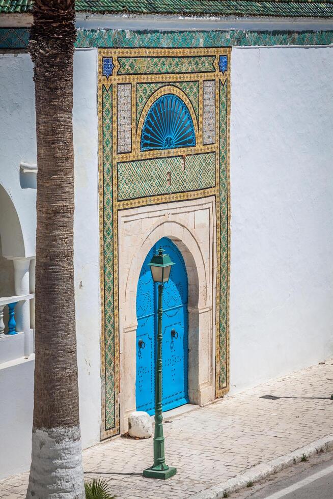 A blue door with black studs and stone ornament at doorway in Tunisia photo