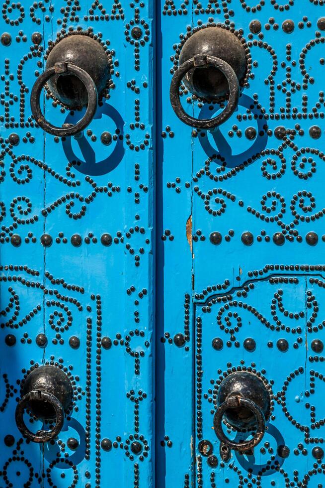 A blue door with black studs and stone ornament at doorway in Tunisia photo