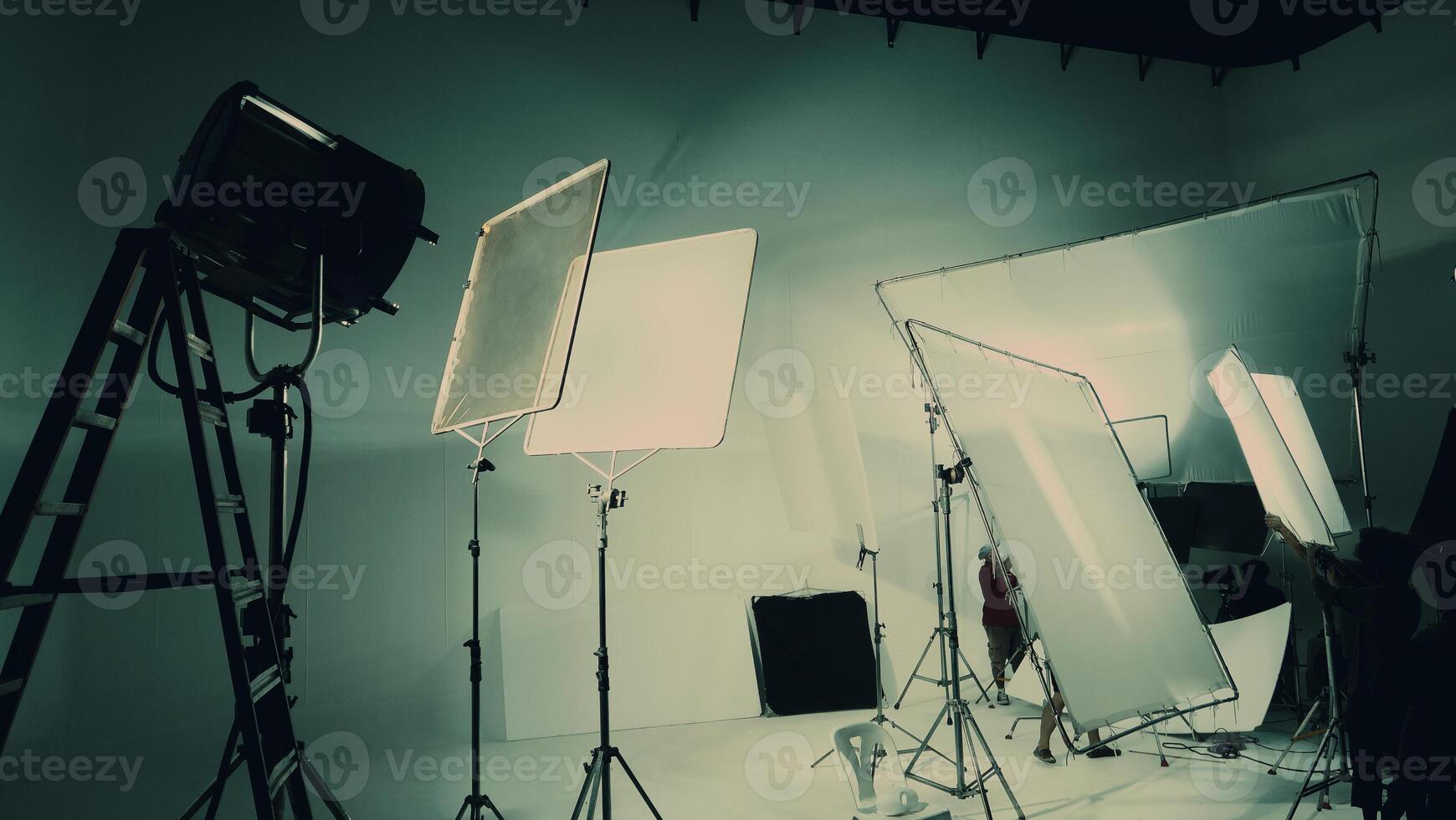 Silhouette of video production behind the scenes or B roll or making of TV commercial movie that film crew team lightman and cameraman working together with director in big studio with pro equipments photo