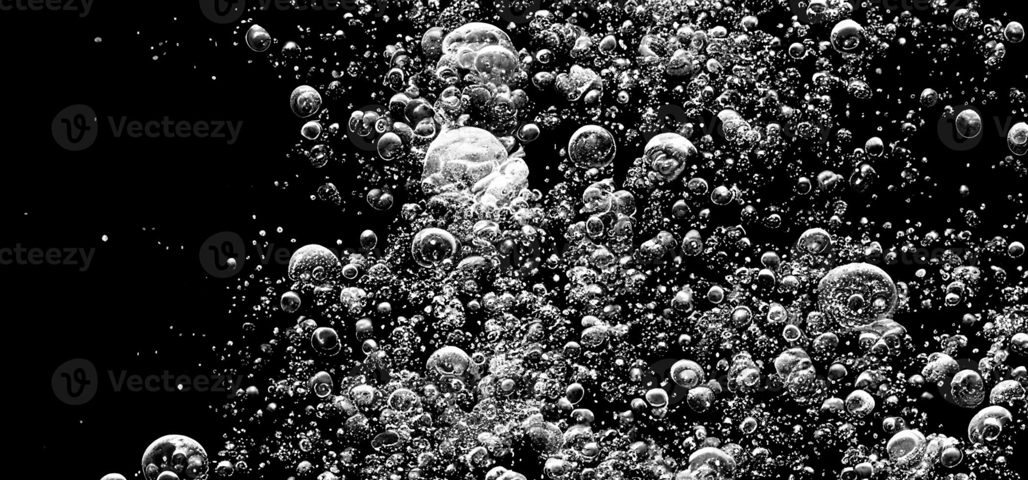 Soda water bubbles splashing underwater against black background. photo