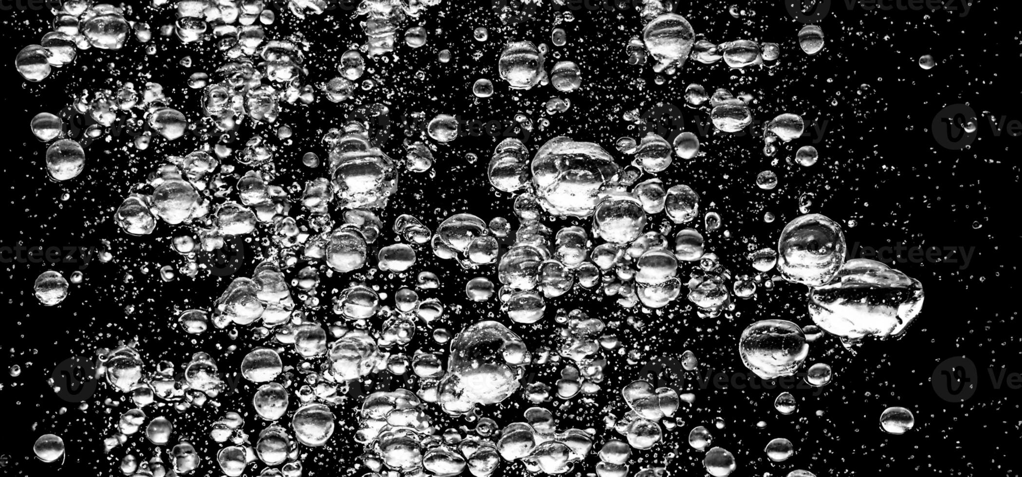 Soda water bubbles splashing underwater against black background. photo