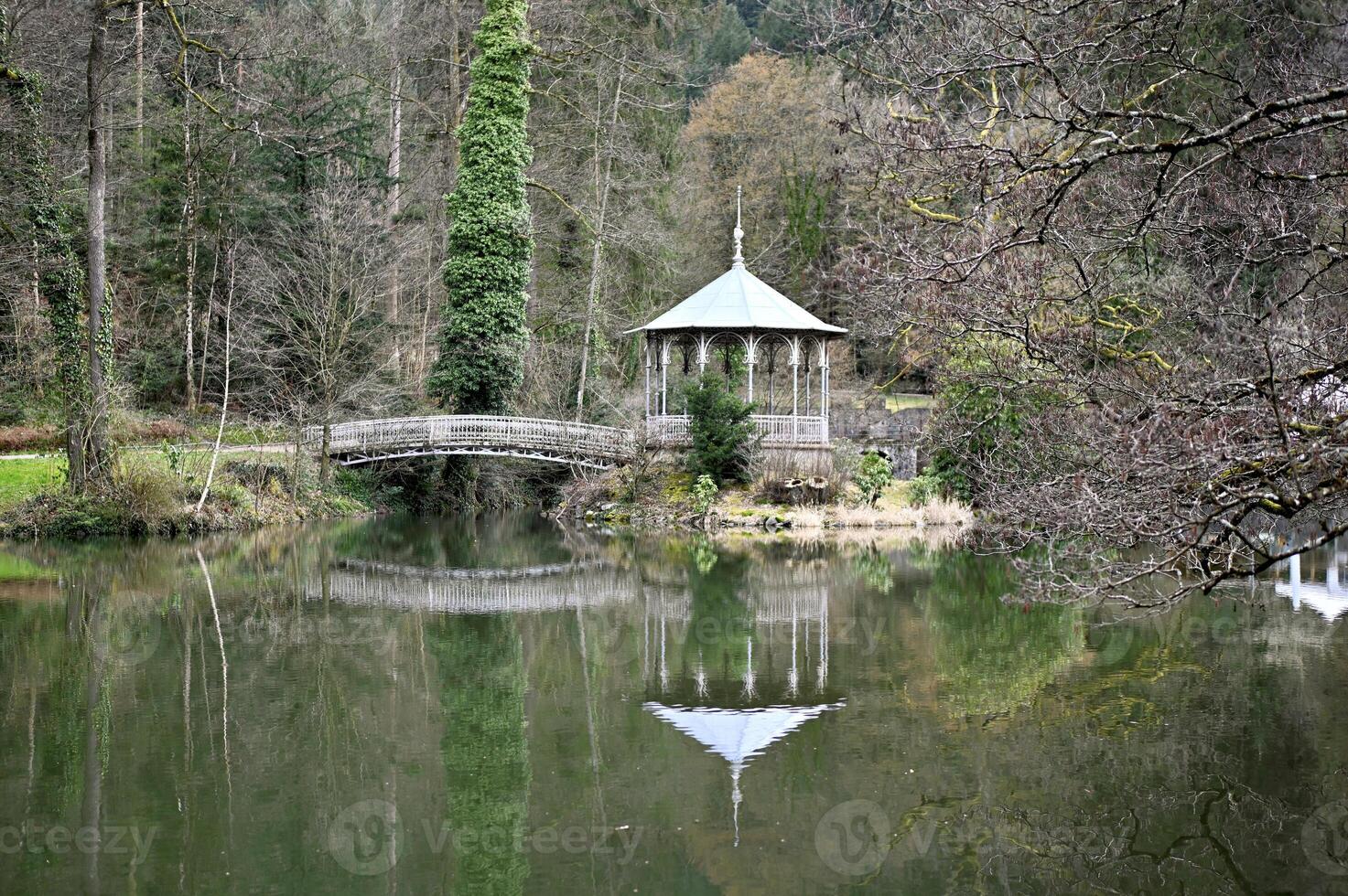 Small island with old pavilion and bridge in the forest lake photo