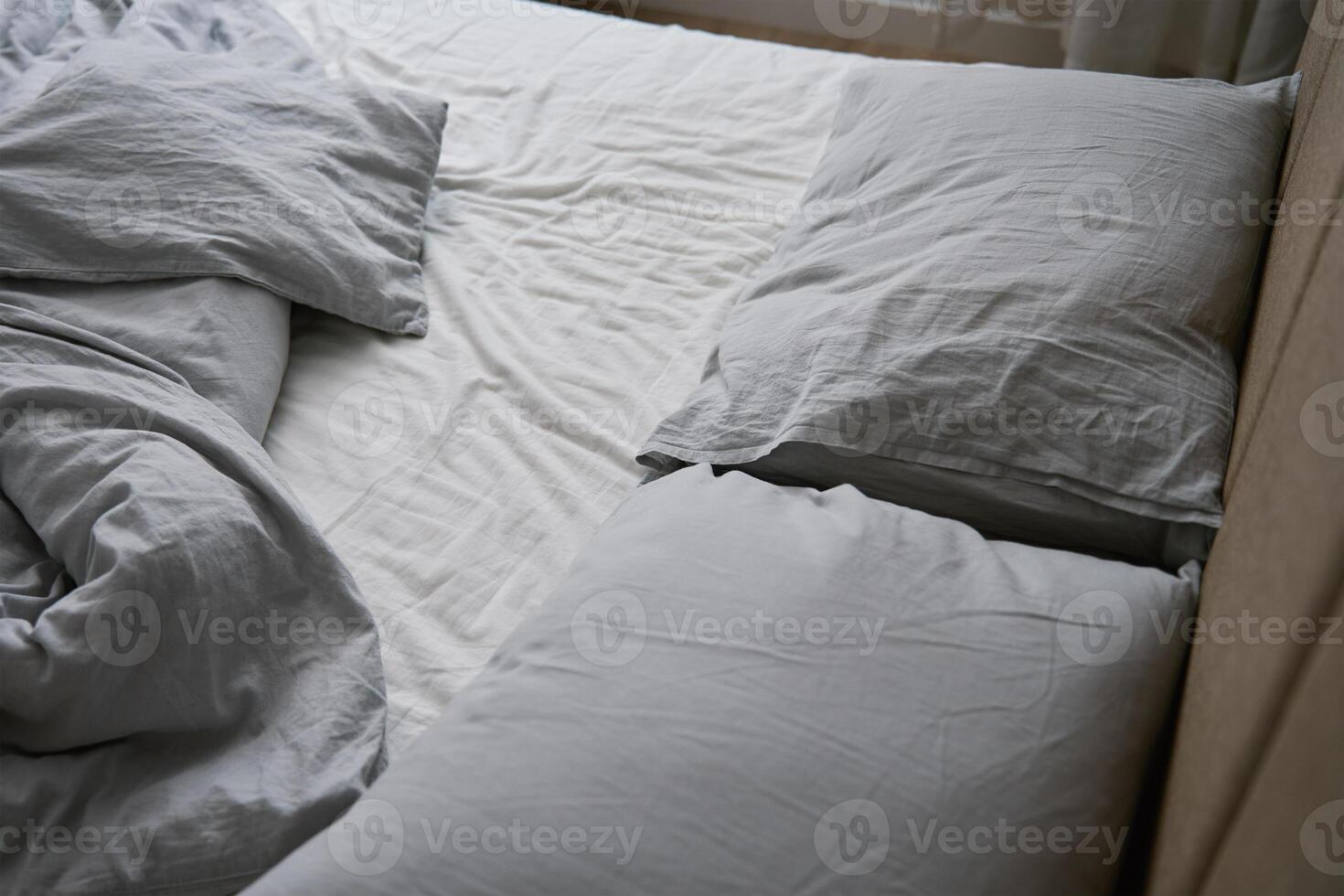 Crumpled bed with pillows, blanket and crumpled sheets in bedroom photo