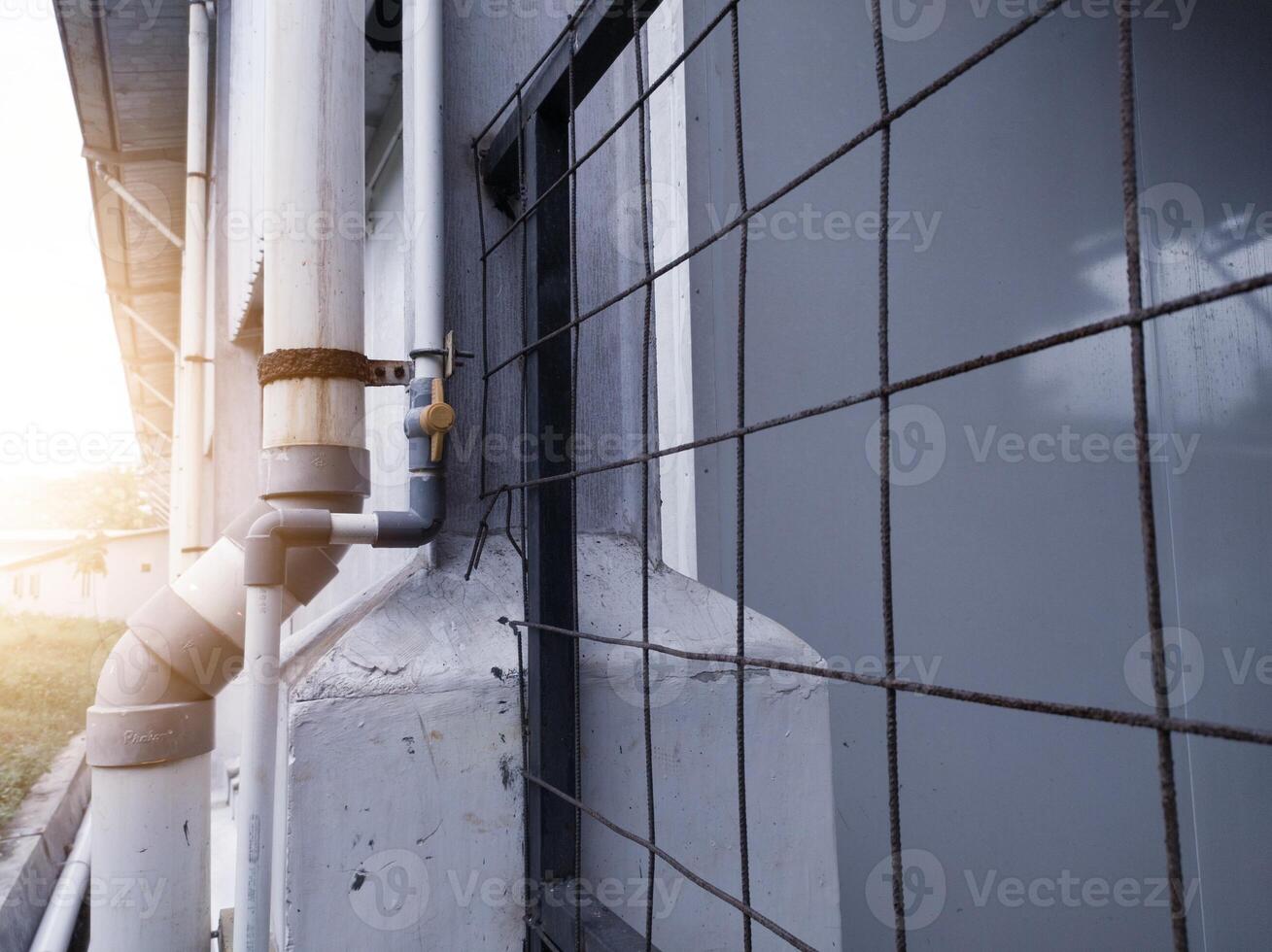 Gutter drainage pipes and clean water supply pipes attached to the outside of the factory building. photo