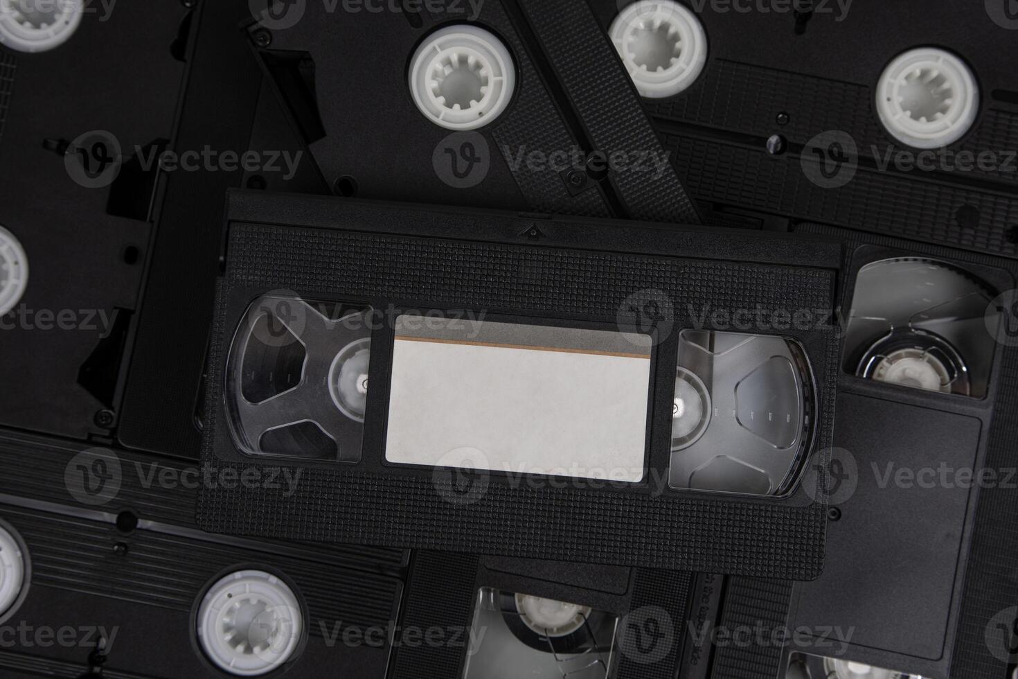 filmar con una videocámara con blanco etiquetas pila de vhs vídeo casetes Clásico medios de comunicación. aislar en un blanco espalda foto