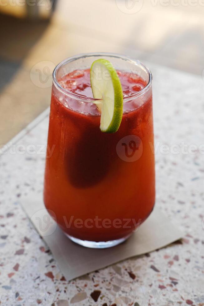 An icy non-alcoholic fruit mocktail topped with a slice of lime. Vertical photo