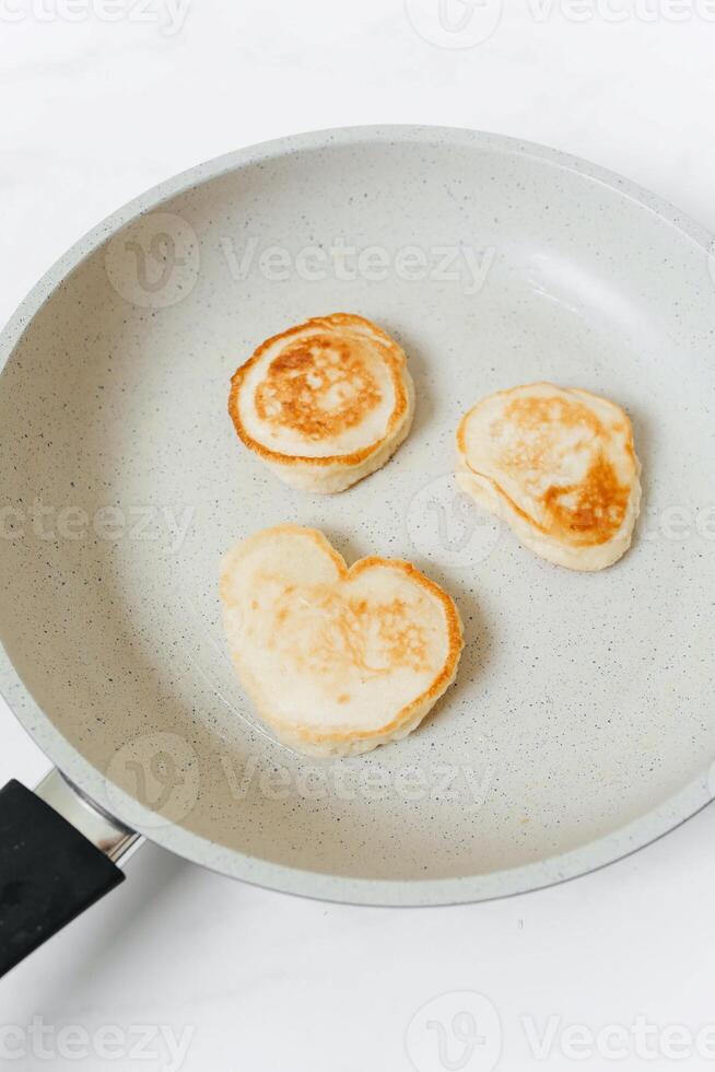 Fried pancakes in a frying pan on a white background, top view photo