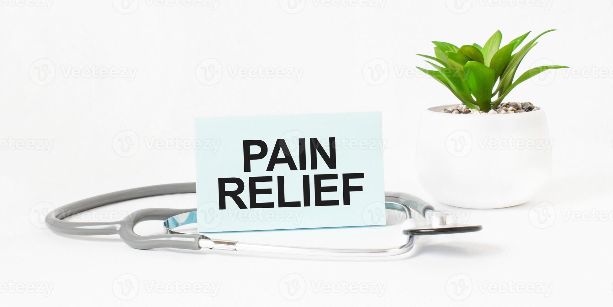 Pain relief card with stethoscope and green plant in white pot on white background. Medical concept for design and print. photo