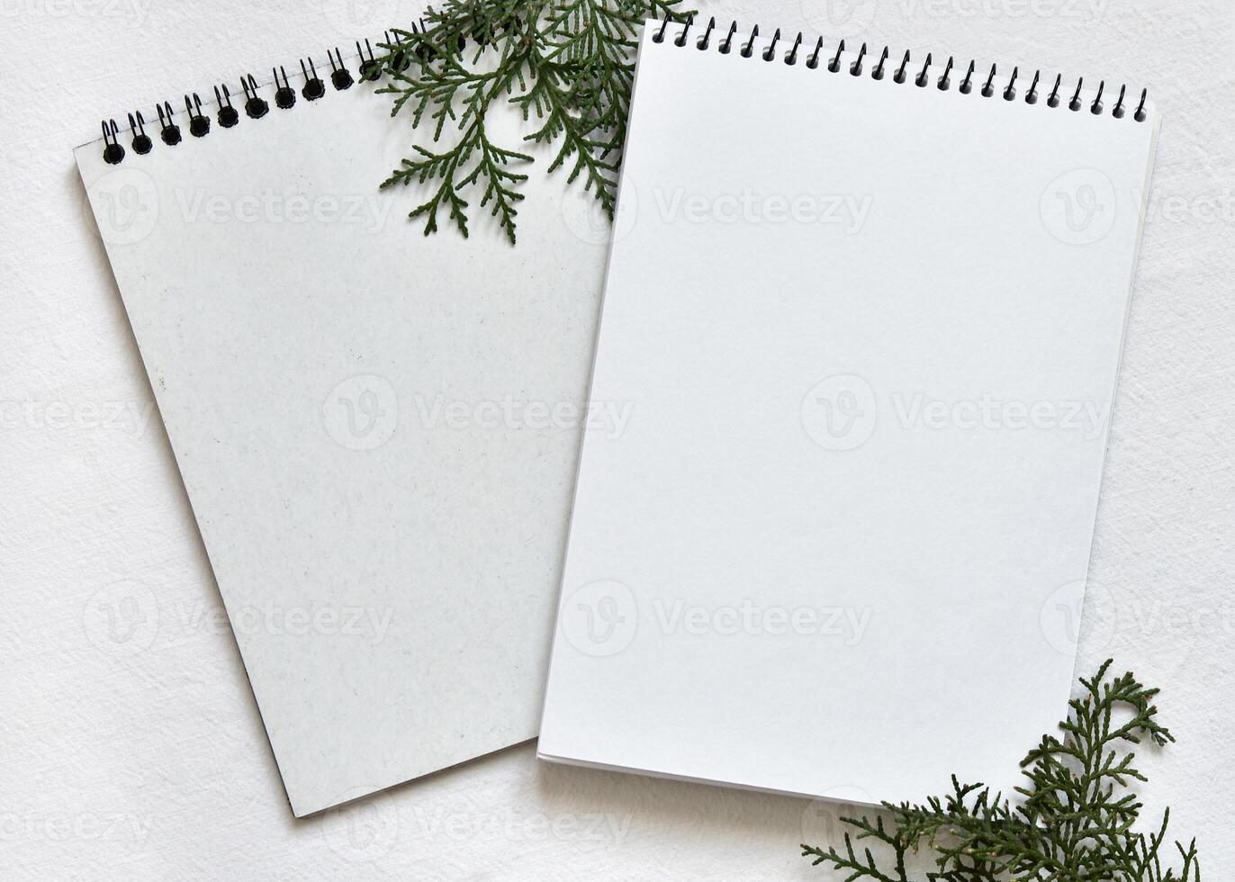 two white sketchbooks on a spring lying on a linen tablecloth with sprigs of green thuja photo