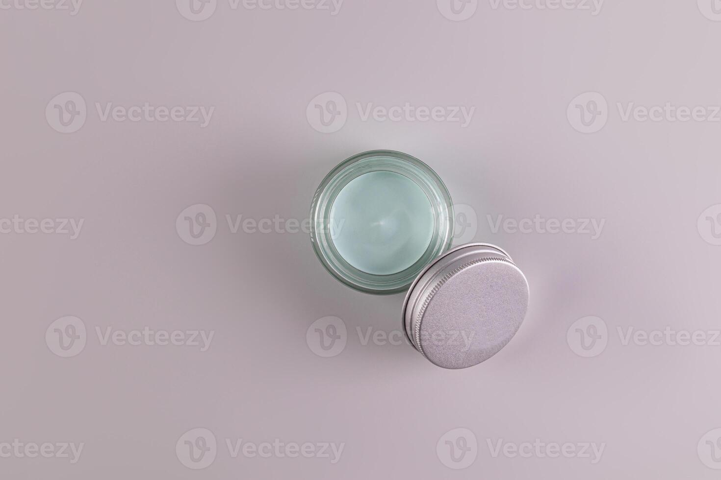 Top view of an open jar of a cosmetic product with a delicate blue texture for everyday face and body skin care. spa. massage. Gray background photo