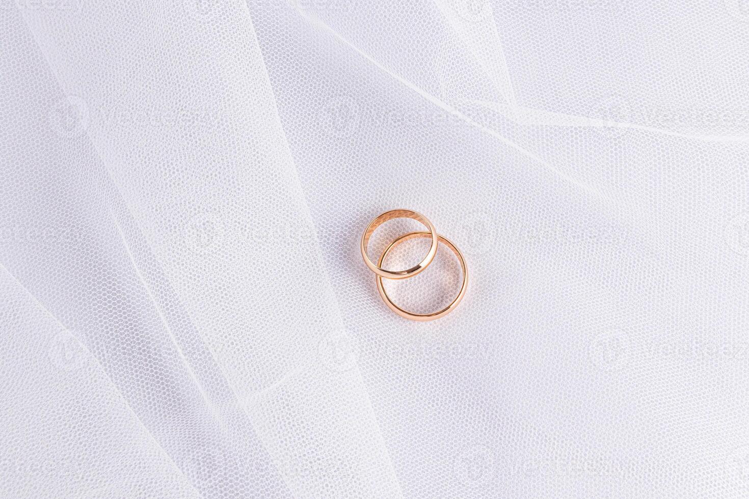 Two gold wedding rings lie on the folds of a white classic bridal veil. Wedding background for design. minimalism. A copy space. postcard. invitation. photo