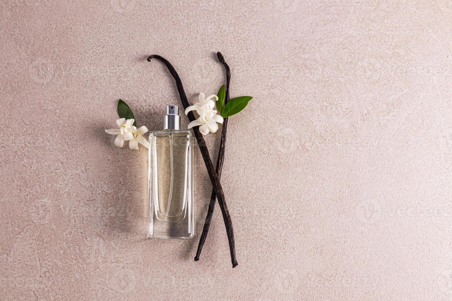 An elegant bottle with a delicate fragrance of women's perfume lies on the vanilla sticks. Presentation of the fragrance. Top view. A copy space. photo