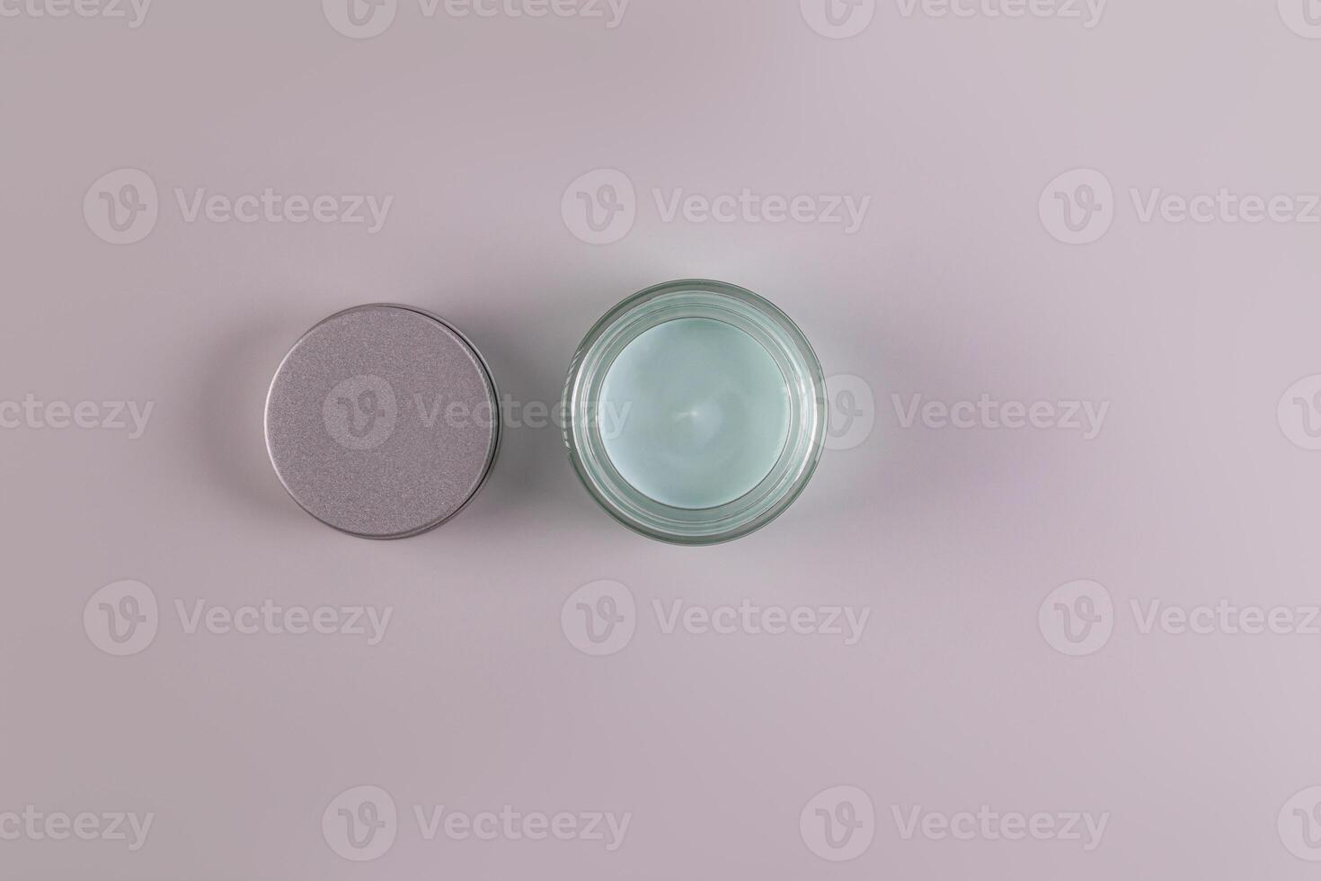 Top view of an open jar of a cosmetic product with a delicate blue texture for everyday face and body skin care. spa. massage. Gray background. photo