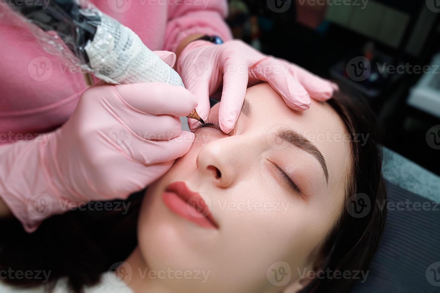 A girl with her eyes closed is lying down for a permanent eyelash makeup procedure. Permanent eye makeup and PMU eyelashes photo