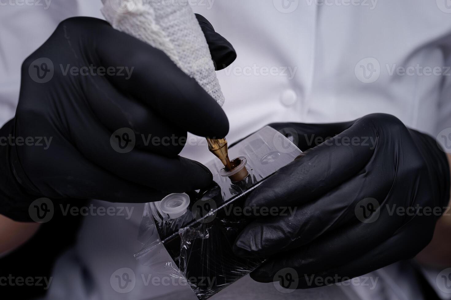 Close-up of the hands of the master, who holds a tattoo machine and dials pigment into it. PMU Procedure, Permanent Eyebrow Makeup. photo