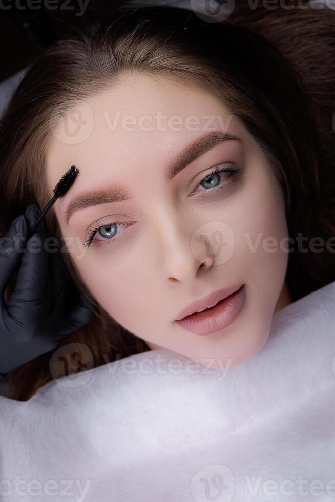 Result after permanent eyebrow makeup master brushes the eyebrows with a brush. PMU Procedure, Permanent Eyebrow Makeup. photo