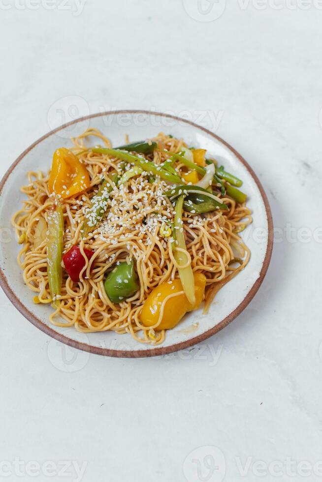 Noodles with vegetables in a plate on a white background. photo