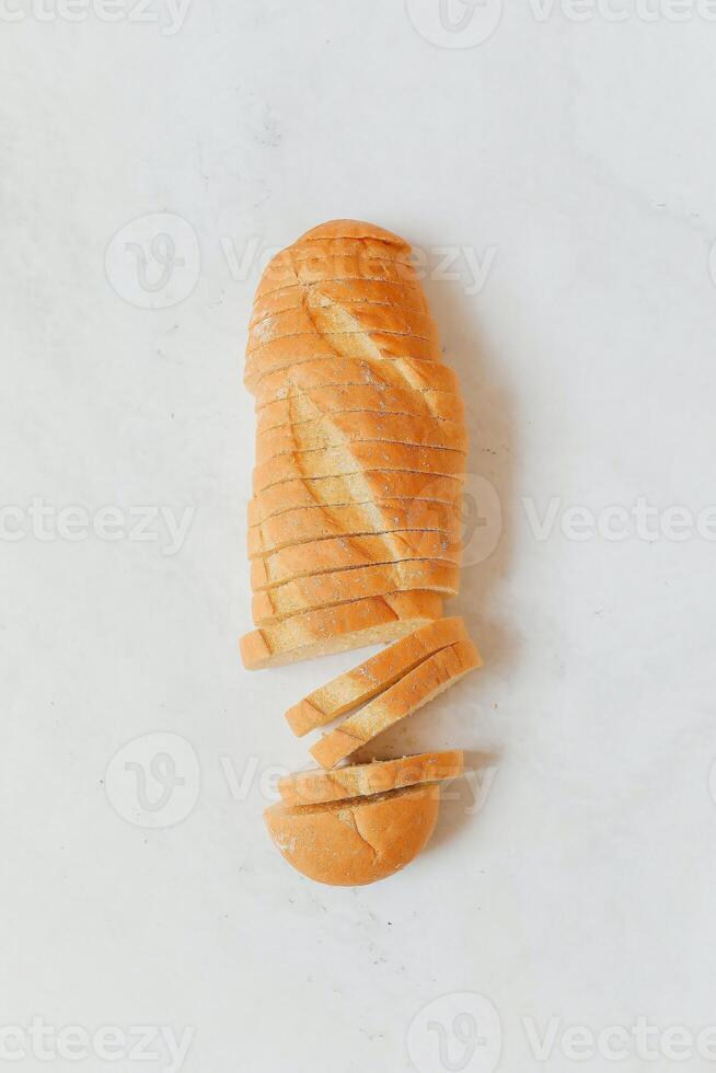 Sliced baguette on white marble background, top view photo