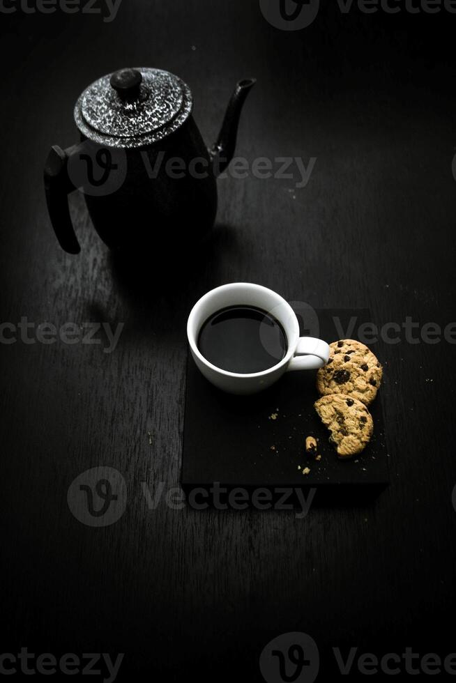 Cup of coffee and cookies on black table. Toned. photo
