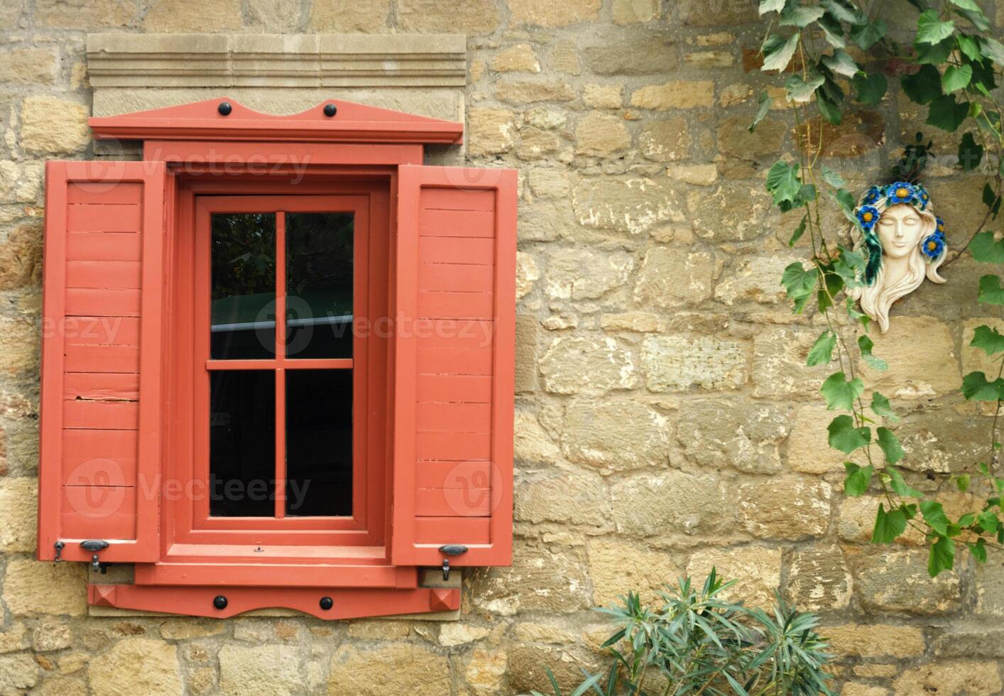 Red Window Shutters and Stone Wall with Sculpture photo